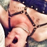 I am lying on my back. Wearing a framed bra. There is writing on my body - good girl, plus tally lines denoting orgasms. My mouth is open and Master's cock hovers above.