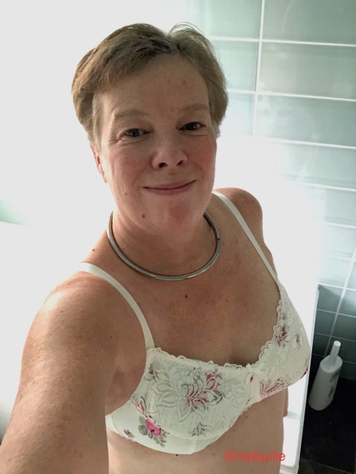 I'm in the bathroom wearing a white bra with pink roses, a collar and a smile!