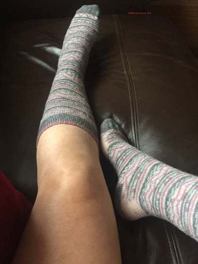 Long socks, they are grey, pink and white patterned. A little threadbare around the heels. You can seem my left knee and thigh.