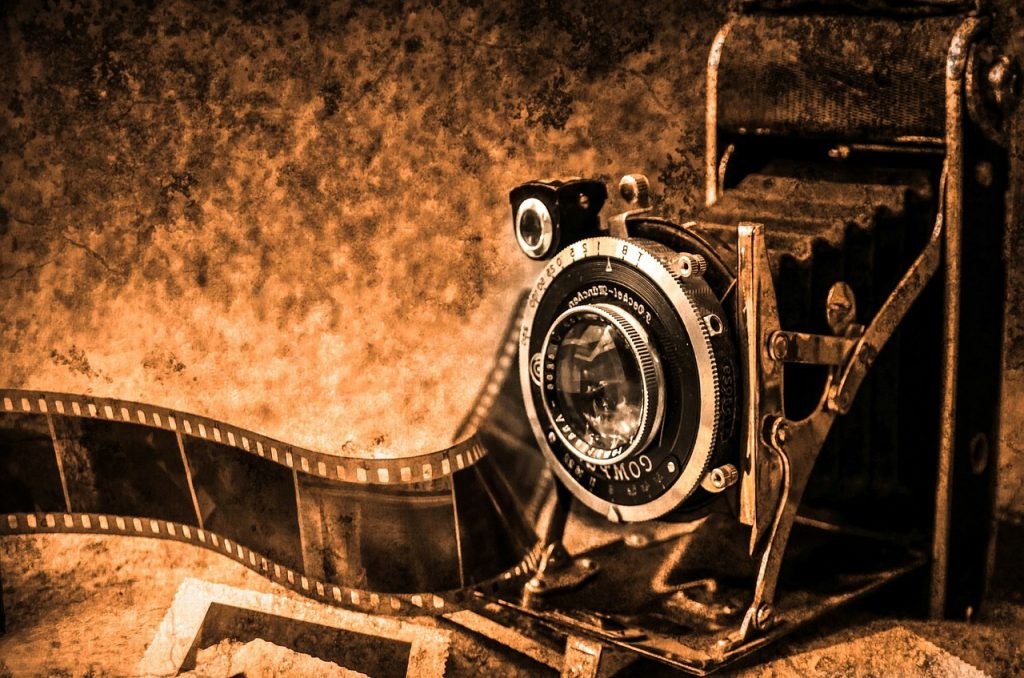 An image of an old box brownie camera with negative film. Set into a brown background.