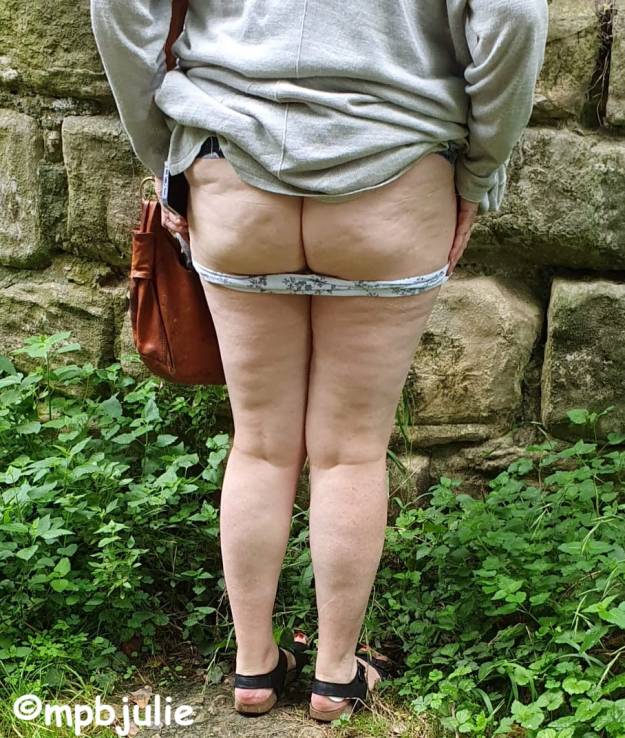 Me with my dress and cardigan around my waist, bum and legs showing. I'm in front of a wall.