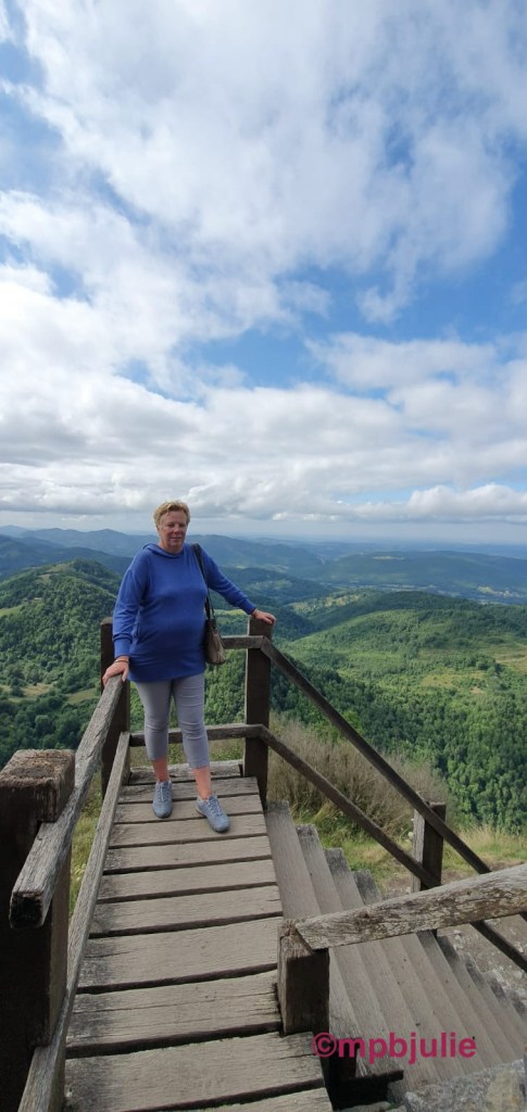 At the end of a wooden landing looking over the view at Montsegur. I'm fully clothed in cropped trousers and a purpled sweatshirt.