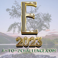 E 2023 in gold lettering. There's a tree, sky. and hills behind. 