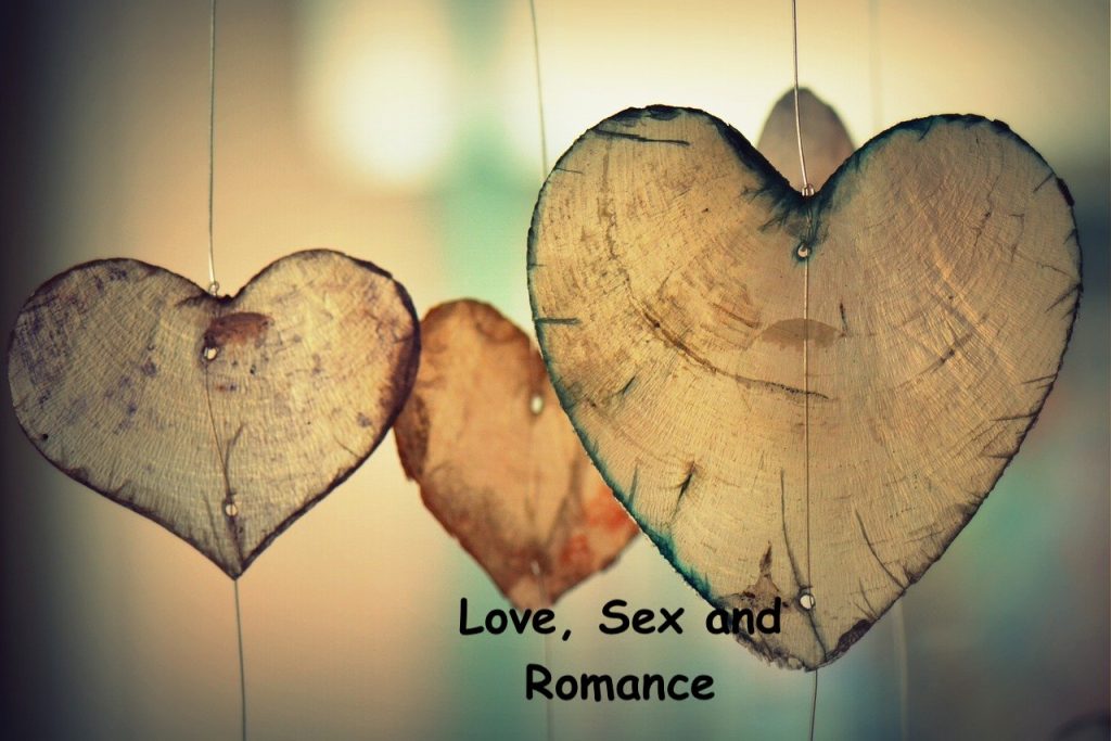 Three semi transparent wooden hearts. Love, sex and romance is written below.