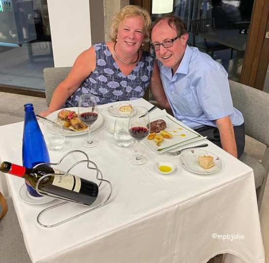 We are sitting at. 2 corners of a table eating dinner outside a restaurant in summer. We are in Spain on honeymoon. 