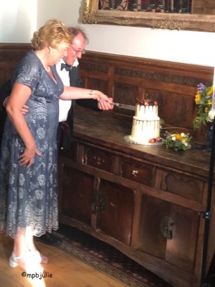 We are cutting the cake. it is 2 tiers with fruit on top.