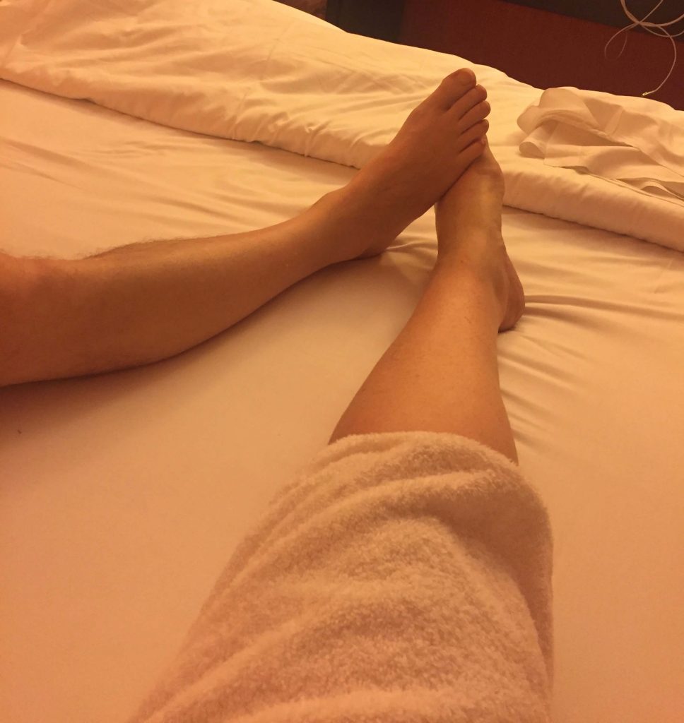 A photo of us lying in bed with our feet touching. All you can see is the bed and our two legs. 