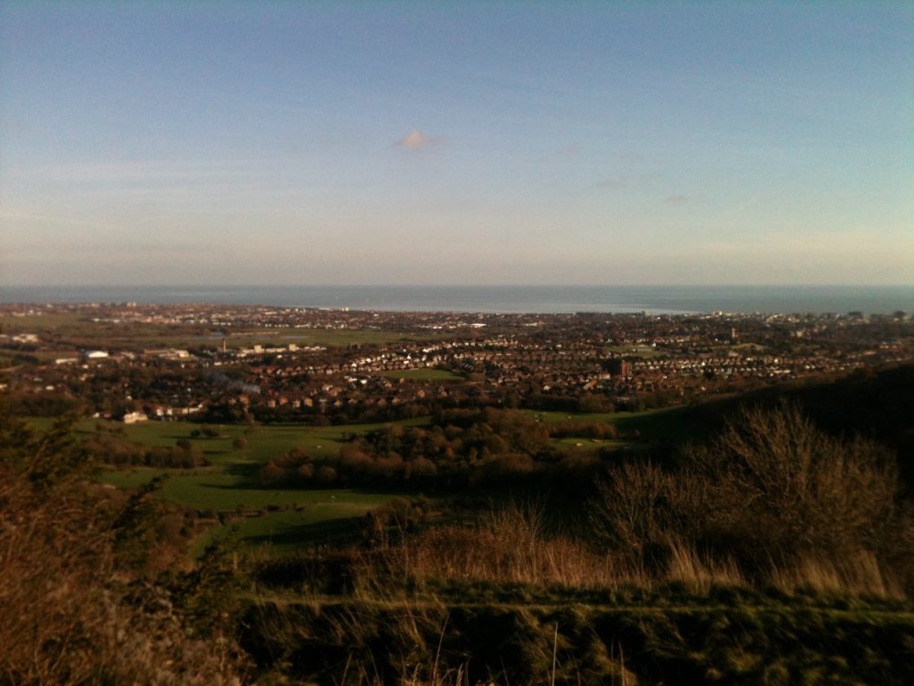 A scene taken from some hills on South Coast of England. Town and sea in the distance.