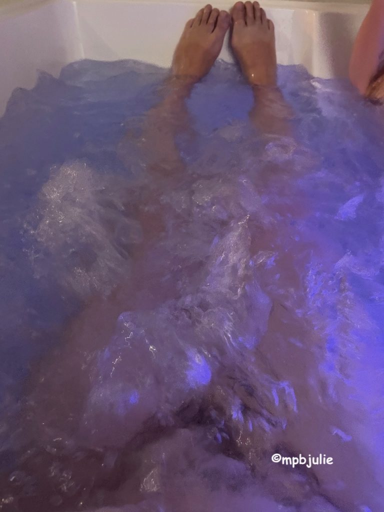 My legs in the jacuzzi bath. The water looks purple because of the lighting. 