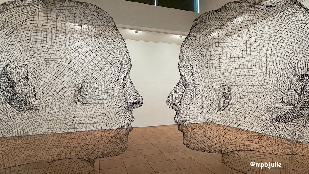 Two heads made of mesh. They are not quite facing each other. Photographed in the art museum in Ceret France. 